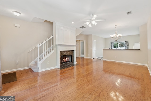 13495 Spring View Dr, Alpharetta, GA 30004 - unfurnished living room with light wood-style flooring, a chandelier, a ceiling fan, stairs, and a premium fireplace