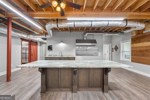 735 Firetower Rd, Thomaston, GA 30286 - kitchen with light wood-style flooring, a ceiling fan, a breakfast bar, light stone countertops, and a kitchen island