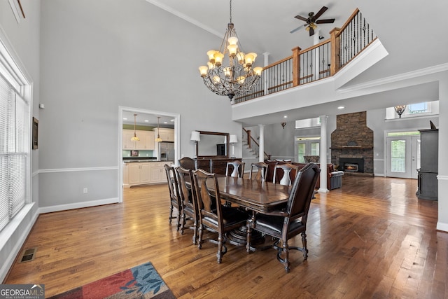 735 Firetower Rd, Thomaston, GA 30286 - dining room featuring light wood-style floors, a high ceiling, a stone fireplace, ceiling fan, and stairs