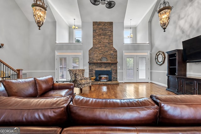 735 Firetower Rd, Thomaston, GA 30286 - living area featuring a towering ceiling, wood finished floors, a chandelier, a stone fireplace, and french doors