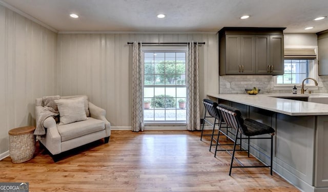 595 Glenforest Rd, Sandy Springs, GA 30328 - kitchen featuring crown molding, a breakfast bar area, light wood finished floors, tasteful backsplash, and light stone countertops
