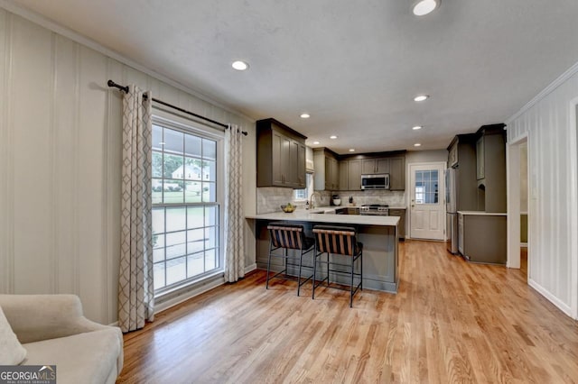 595 Glenforest Rd, Sandy Springs, GA 30328 - kitchen featuring stainless steel appliances, ornamental molding, a peninsula, light wood-type flooring, and a kitchen bar