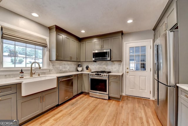 595 Glenforest Rd, Sandy Springs, GA 30328 - kitchen with stainless steel appliances, gray cabinets, light wood-type flooring, decorative backsplash, and light countertops