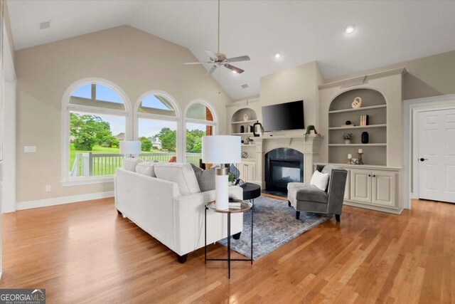 411 Hickory Fairway Ct, Woodstock, GA 30188 - living area featuring a ceiling fan, a glass covered fireplace, light wood finished floors, vaulted ceiling, and built in shelves