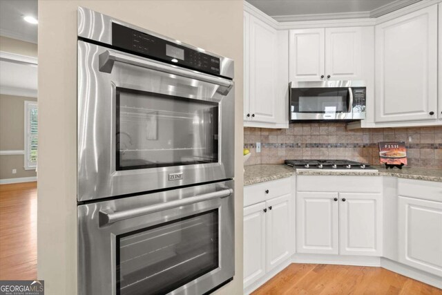 411 Hickory Fairway Ct, Woodstock, GA 30188 - kitchen with stainless steel appliances, light wood finished floors, tasteful backsplash, white cabinets, and ornamental molding
