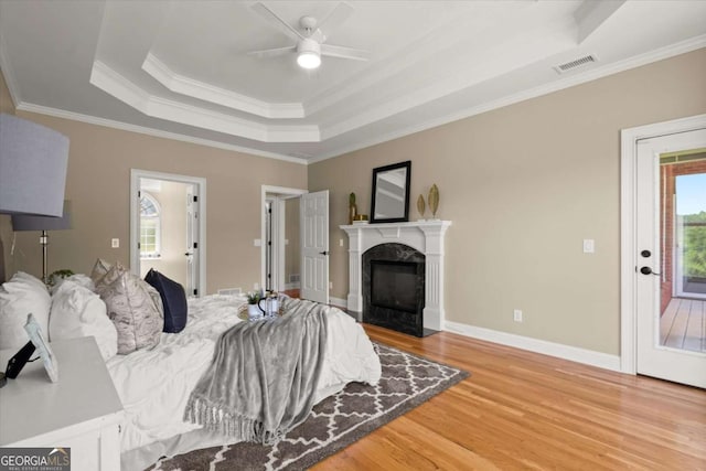 411 Hickory Fairway Ct, Woodstock, GA 30188 - bedroom featuring a tray ceiling, light wood-style flooring, crown molding, a fireplace, and access to exterior