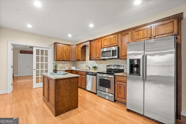 411 Hickory Fairway Ct, Woodstock, GA 30188 - kitchen with stainless steel appliances, a kitchen island, light wood-style floors, french doors, and light stone countertops