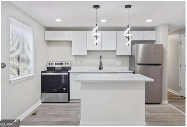 2106 Singer Way, Lithonia, GA 30058 - kitchen featuring stainless steel appliances, a center island, light wood-style floors, white cabinets, and recessed lighting