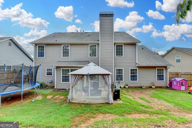 1811 Alberta Ln, Winder, GA 30680 - back of property featuring a trampoline, a gazebo, a chimney, and roof with shingles