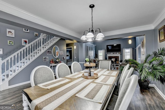 1811 Alberta Ln, Winder, GA 30680 - dining room featuring stairs, dark wood-style floors, ornamental molding, a chandelier, and a fireplace
