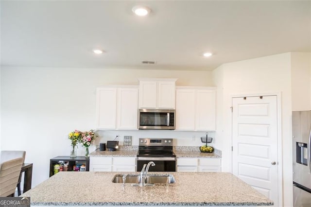 2159 Redfern, Dacula, GA 30019 - kitchen featuring stainless steel appliances, a kitchen island with sink, white cabinetry, light stone counters, and recessed lighting