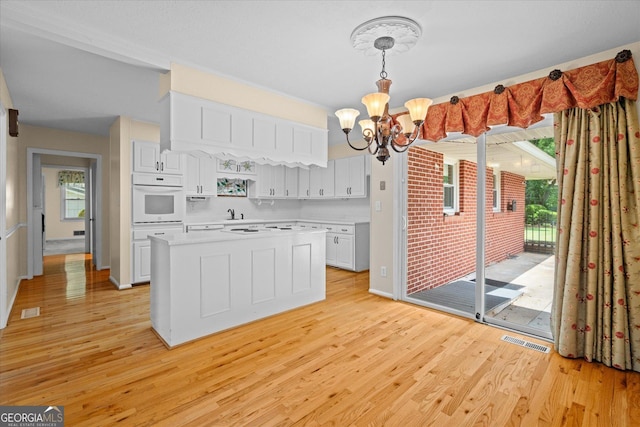 106 Lakeview Dr, Carrollton, GA 30117 - kitchen with oven, a chandelier, light countertops, light wood-style floors, and white cabinetry