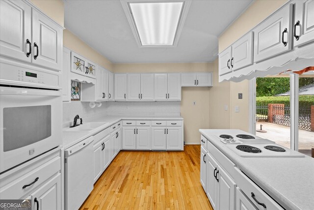 106 Lakeview Dr, Carrollton, GA 30117 - kitchen with white appliances, white cabinets, light countertops, light wood-style floors, and backsplash