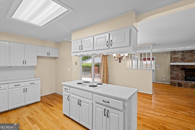 106 Lakeview Dr, Carrollton, GA 30117 - kitchen with white electric cooktop, light countertops, light wood-style floors, white cabinets, and a stone fireplace