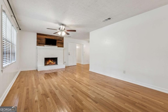 3123 Deshong Dr, Stone Mountain, GA 30087 - unfurnished living room featuring light wood-type flooring, ceiling fan, a brick fireplace, and a textured ceiling