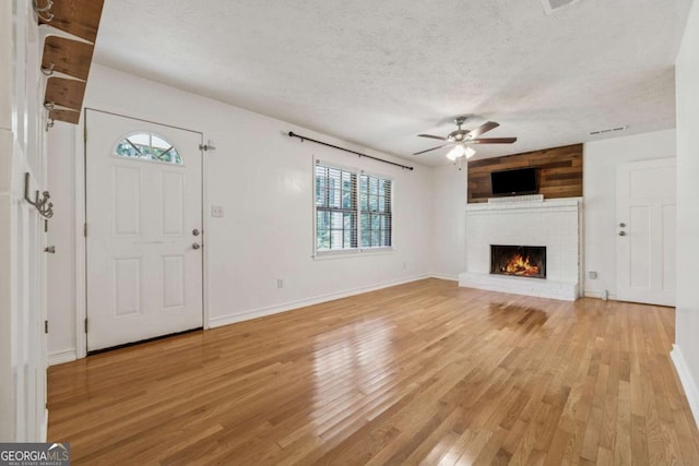 3123 Deshong Dr, Stone Mountain, GA 30087 - unfurnished living room featuring ceiling fan, light wood-style floors, a textured ceiling, and a fireplace