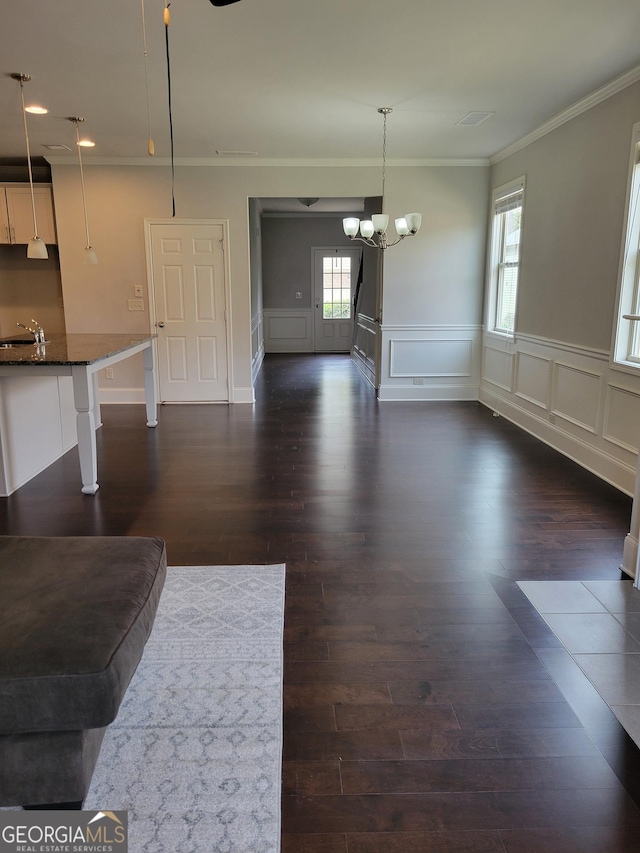 2424 Saint Andrews Rdg, College Park, GA 30337 - unfurnished living room with crown molding, a chandelier, dark wood-style flooring, a wainscoted wall, and a decorative wall