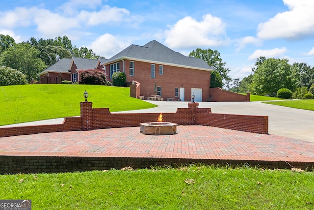 152 Lace Field Ln, Lavonia, GA 30553 - rear view of property featuring a yard, an outdoor fire pit, concrete driveway, a patio area, and brick siding