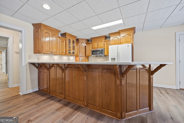 152 Lace Field Ln, Lavonia, GA 30553 - kitchen featuring white refrigerator with ice dispenser, stainless steel microwave, glass insert cabinets, light wood finished floors, and a breakfast bar