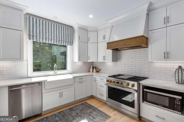 5414 Manteo Inlt, Peachtree Corners, GA 30092 - kitchen with appliances with stainless steel finishes, premium range hood, light wood-style flooring, white cabinetry, and decorative backsplash
