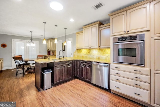 186 Ashley Dr, Mcdonough, GA 30252 - kitchen featuring appliances with stainless steel finishes, a peninsula, light wood-style floors, crown molding, and light stone counters
