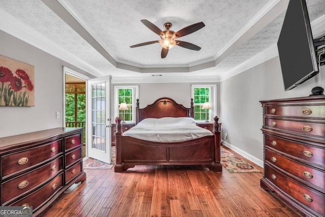 186 Ashley Dr, Mcdonough, GA 30252 - bedroom featuring wood-type flooring, access to exterior, a tray ceiling, a ceiling fan, and ornamental molding