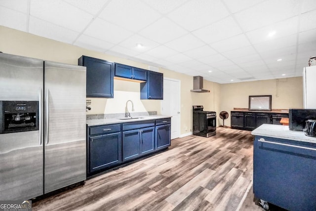 186 Ashley Dr, Mcdonough, GA 30252 - kitchen with stainless steel fridge with ice dispenser, gas range oven, blue cabinetry, wall chimney range hood, and light countertops