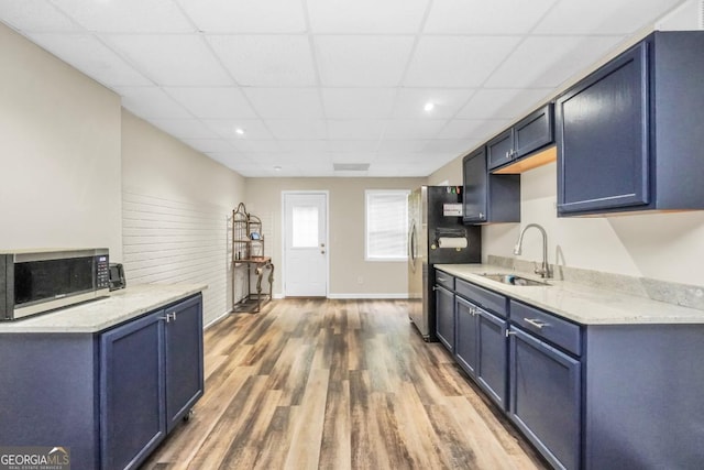 186 Ashley Dr, Mcdonough, GA 30252 - kitchen with stainless steel appliances, wood finished floors, a paneled ceiling, blue cabinetry, and light stone countertops