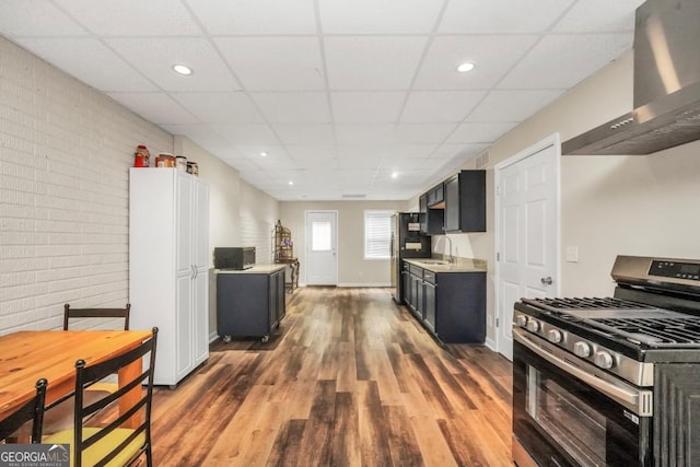 186 Ashley Dr, Mcdonough, GA 30252 - kitchen with stainless steel appliances, wall chimney exhaust hood, a drop ceiling, wood finished floors, and dark cabinetry