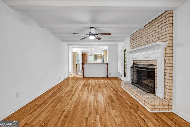 2585 Regency Dr E, Tucker, GA 30084 - unfurnished living room with beamed ceiling, wood finished floors, a brick fireplace, and a ceiling fan