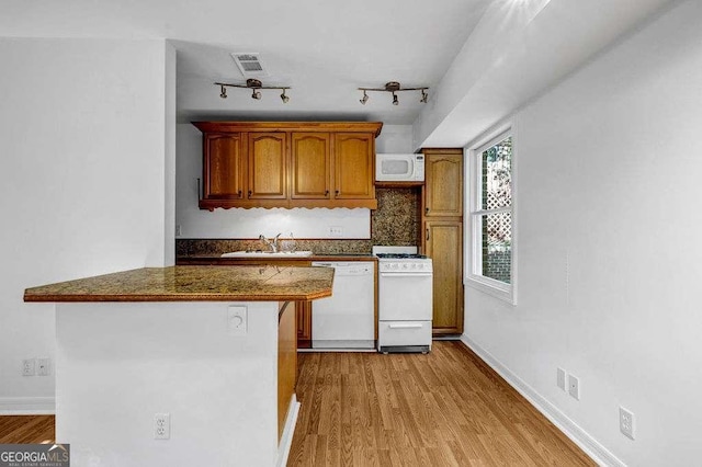 2585 Regency Dr E, Tucker, GA 30084 - kitchen featuring white appliances, light wood-style flooring, backsplash, and brown cabinets