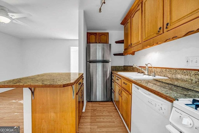 2585 Regency Dr E, Tucker, GA 30084 - kitchen with freestanding refrigerator, white dishwasher, light wood finished floors, brown cabinetry, and stove