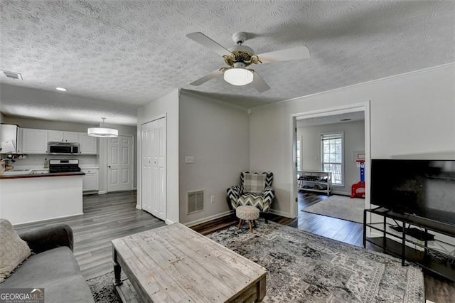 5385 Spotted Fawn Ct, Suwanee, GA 30024 - living room featuring wood finished floors, a textured ceiling, a ceiling fan, and crown molding