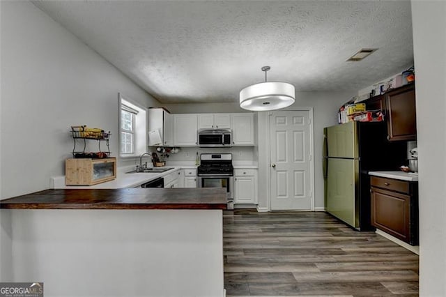 5385 Spotted Fawn Ct, Suwanee, GA 30024 - kitchen with appliances with stainless steel finishes, dark wood-type flooring, a peninsula, white cabinets, and hanging light fixtures