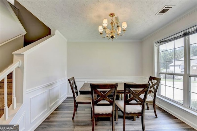 5385 Spotted Fawn Ct, Suwanee, GA 30024 - dining space featuring a chandelier, wood finished floors, a textured ceiling, wainscoting, and crown molding