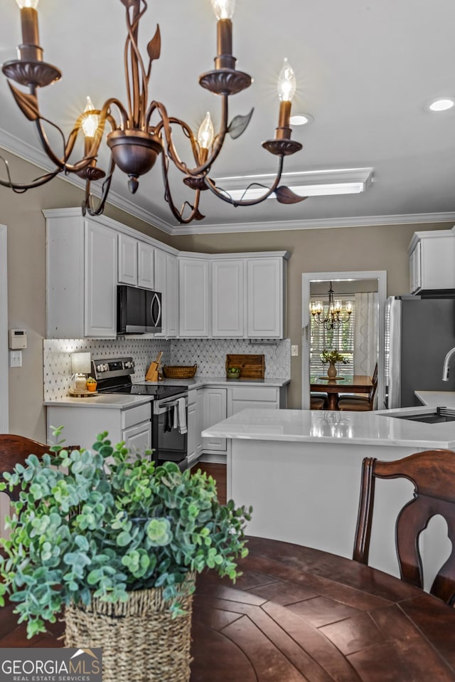 1120 Liberty Ln, Bogart, GA 30622 - kitchen featuring stainless steel appliances, a chandelier, crown molding, light countertops, and white cabinets