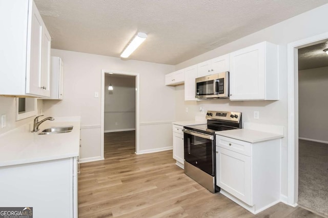 1024 Stone Mill Run, Lawrenceville, GA 30046 - kitchen featuring appliances with stainless steel finishes, white cabinetry, light wood-style flooring, light countertops, and a textured ceiling