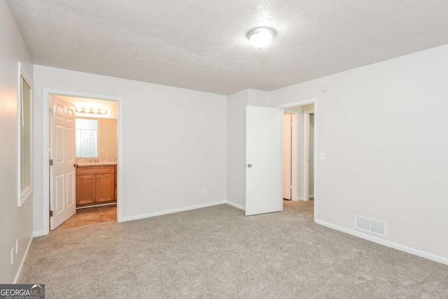 1024 Stone Mill Run, Lawrenceville, GA 30046 - unfurnished bedroom featuring light carpet, a textured ceiling, and ensuite bath