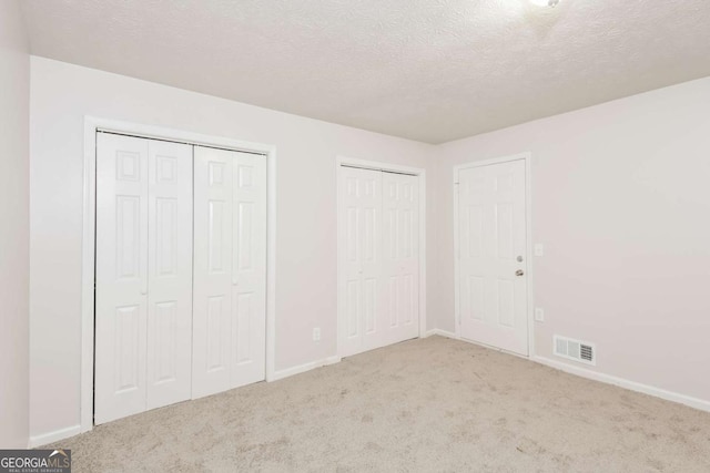 1024 Stone Mill Run, Lawrenceville, GA 30046 - unfurnished bedroom with multiple closets, carpet flooring, and a textured ceiling