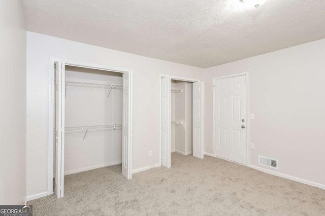 1024 Stone Mill Run, Lawrenceville, GA 30046 - unfurnished bedroom featuring multiple closets, carpet flooring, and a textured ceiling