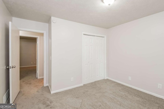 1024 Stone Mill Run, Lawrenceville, GA 30046 - unfurnished bedroom featuring carpet floors, a closet, and a textured ceiling