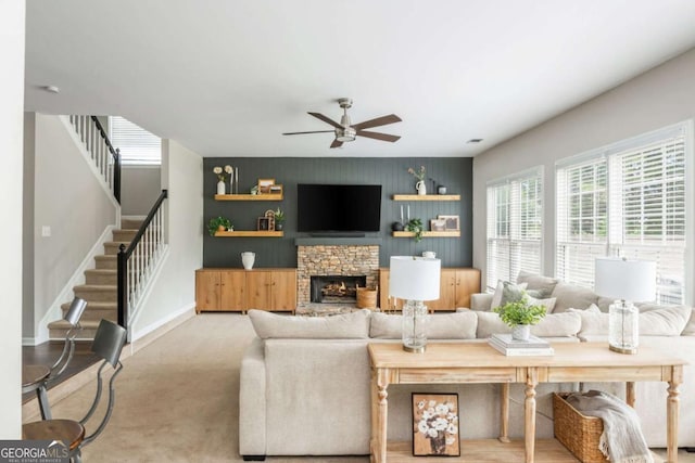 2000 Settindown Dr, Roswell, GA 30075 - carpeted living area with a ceiling fan, stairs, an accent wall, and a stone fireplace