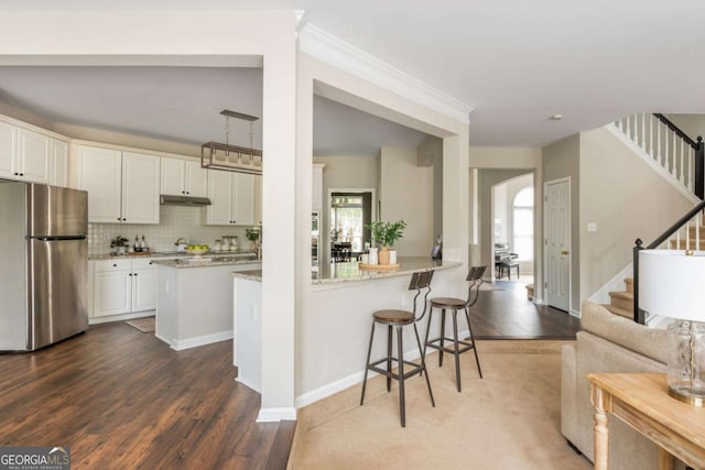 2000 Settindown Dr, Roswell, GA 30075 - kitchen featuring freestanding refrigerator, white cabinetry, dark wood finished floors, arched walkways, and a breakfast bar