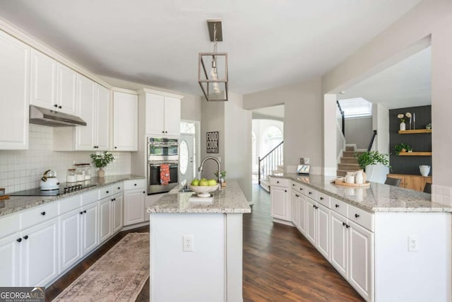 2000 Settindown Dr, Roswell, GA 30075 - kitchen with a center island with sink, stainless steel double oven, black electric cooktop, under cabinet range hood, and white cabinets