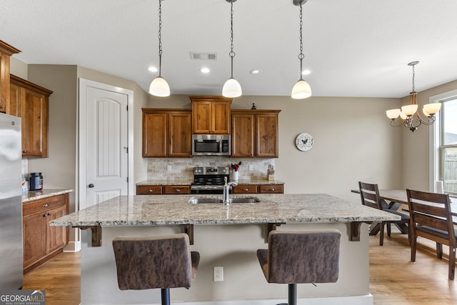 206 Barnyard Way, Perry, GA 31069 - kitchen with stainless steel appliances, brown cabinets, light wood-style floors, backsplash, and a kitchen breakfast bar