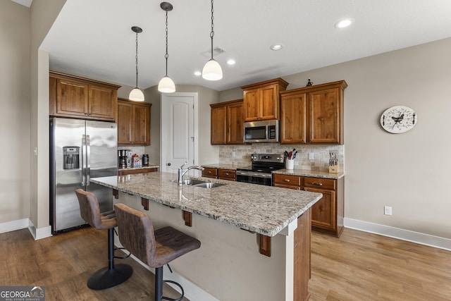 206 Barnyard Way, Perry, GA 31069 - kitchen featuring appliances with stainless steel finishes, brown cabinets, tasteful backsplash, a breakfast bar, and wood finished floors