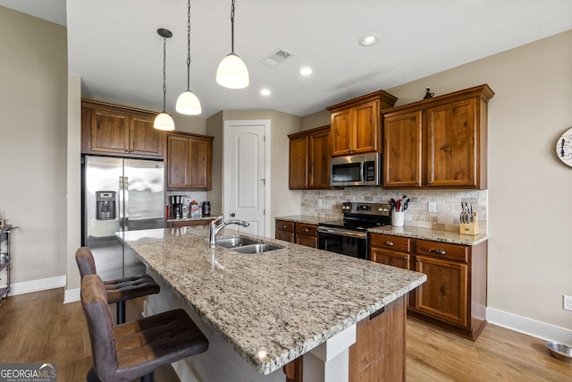 206 Barnyard Way, Perry, GA 31069 - kitchen with appliances with stainless steel finishes, a kitchen breakfast bar, light wood finished floors, decorative backsplash, and recessed lighting
