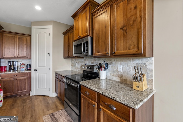 206 Barnyard Way, Perry, GA 31069 - kitchen featuring appliances with stainless steel finishes, tasteful backsplash, light stone countertops, and dark wood finished floors