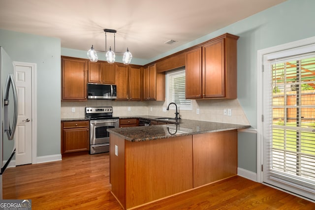 872 Misty View Ct, Lilburn, GA 30047 - kitchen with appliances with stainless steel finishes, brown cabinets, a peninsula, and tasteful backsplash