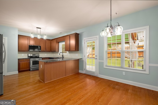 872 Misty View Ct, Lilburn, GA 30047 - kitchen with appliances with stainless steel finishes, a peninsula, a chandelier, backsplash, and light wood-style floors